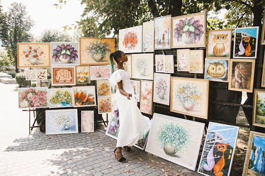 A woman admires various colorful artworks displayed in an outdoor street exhibition.